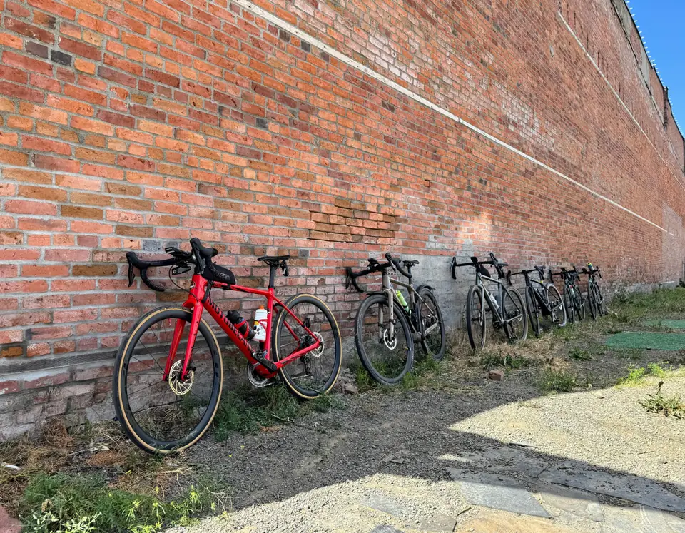 Road bikes lined up beside a brick wall