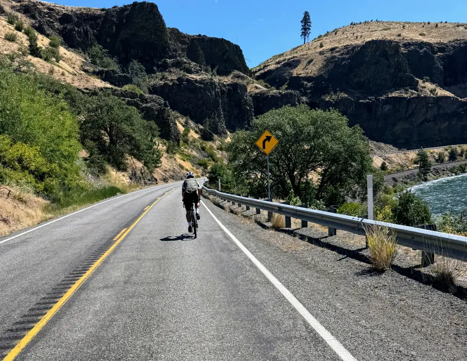 Cyclist riding a scenic road through the Pacific Northwest