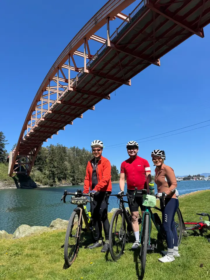 KREW riders with bikes beneath a bridge by the water