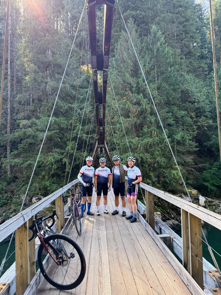 Four KREW riders with bikes on a forest suspension bridge