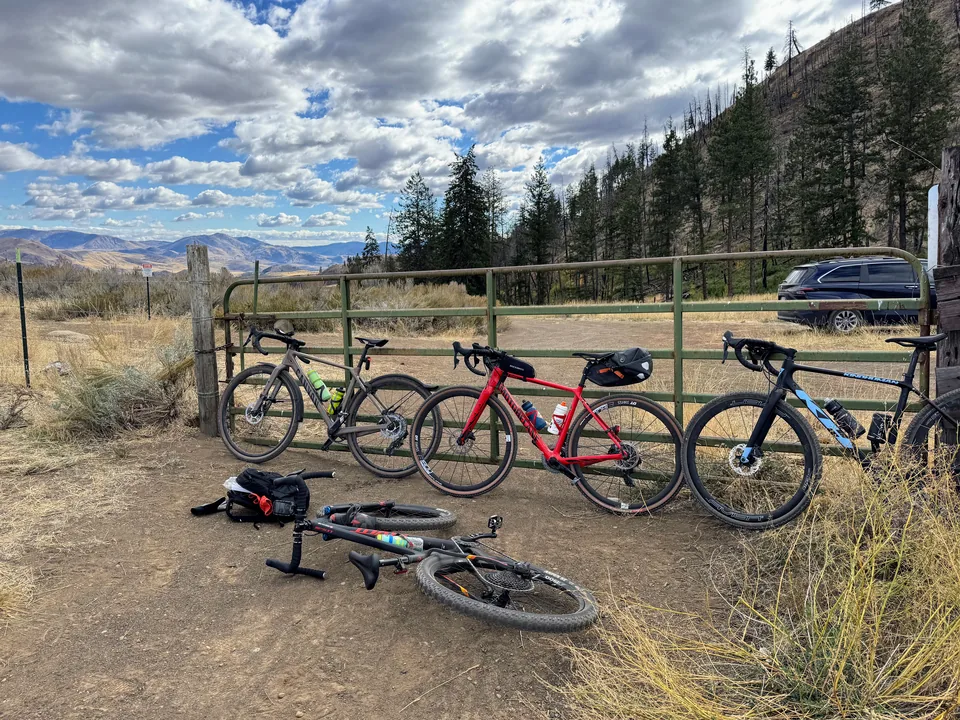 Gravel bikes lined up at a gate in mountain terrain